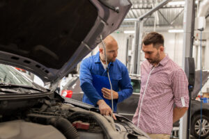 Mechanic with clipboard informing car owner that he purchased a lemon car in California