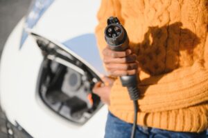 Close up of man next to electric vehicle with charger in hand